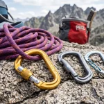 Moschettoni da arrampicata con ghiera a vite e rinvii leggeri appoggiati su roccia alpina