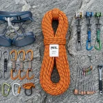 Panoramica flat lay completa di attrezzatura da arrampicata con corda, imbrago, rinvii, moschettoni e scarpette
