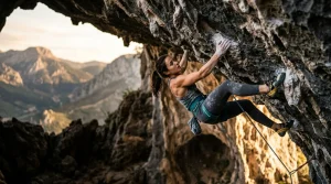 Arrampicatrice atletica esegue movimento in strapiombo severo su roccia calcarea con tallonaggio