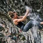 Scalatrice che esegue un tallonaggio e lolotte su strapiombo roccioso calcareo con magnesite